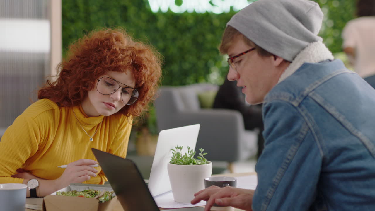 young business people brainstorming beautiful redhead woman using laptop computer sharing ideas showing friend ideas on screen enjoying teamwork in trendy office