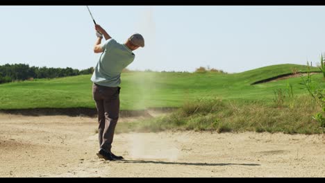 hombre jugando al golf en una trampa de arena