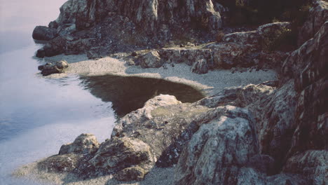 tranquil coastal rock formation at sunset reflecting on the calm water surface