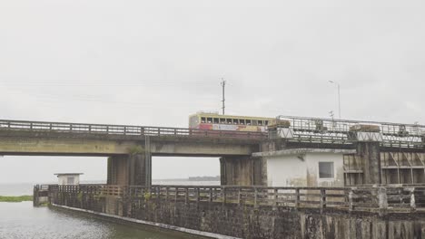 El-Autobús-Pasa-A-Través-De-La-Barrera-Del-Lago,-Tanneermukkam-Bund,-Terraplén-Y-Musgo