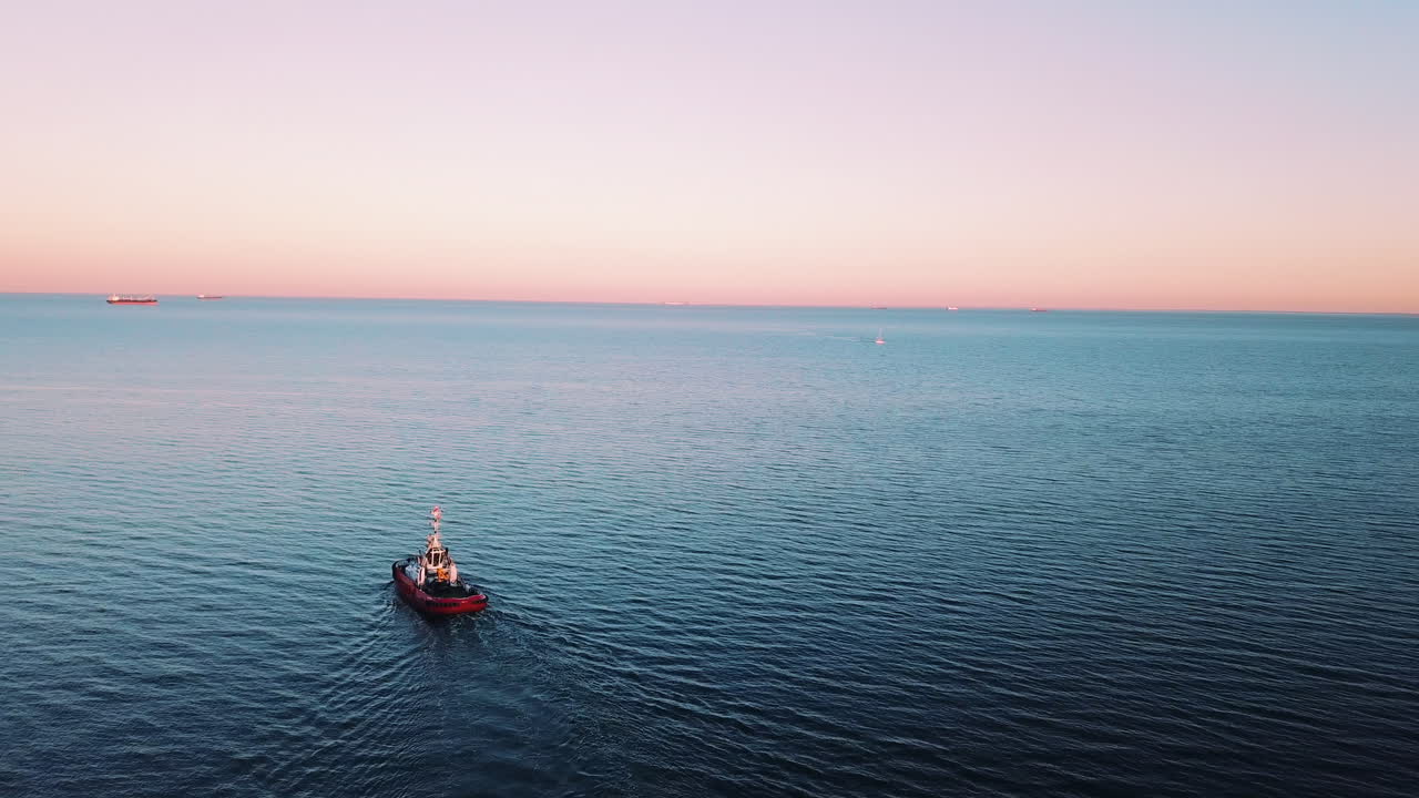 drone volando alrededor de un barco de pesca navegando en el mar al atardecer