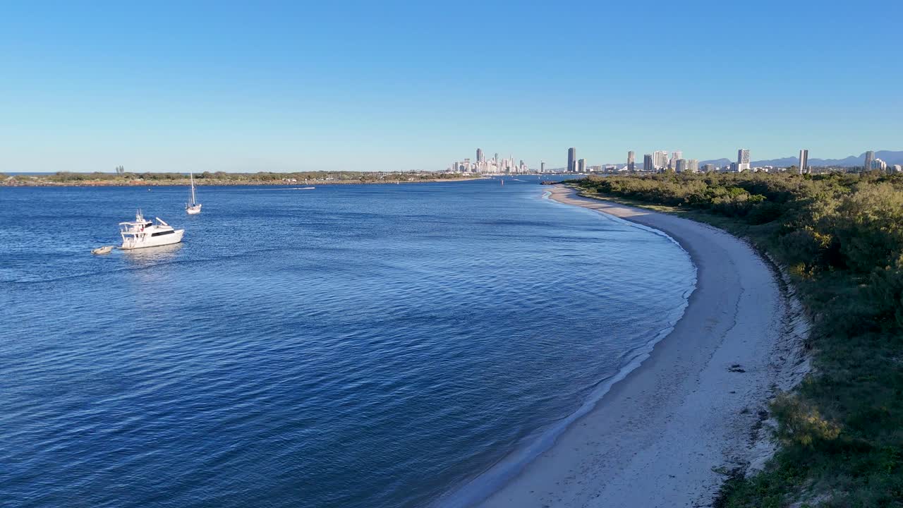 A luxury yacht navigates calm waters near Gold Coast, Australia, under clear blue skies, showcasing serene coastal scenery
