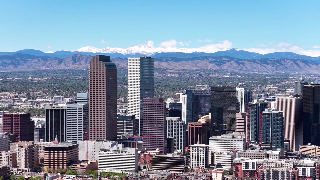 Vista aerea con drone dei grattacieli del centro di Denver con le Montagne Rocciose innevate che si ergono in lontananza.