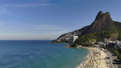 panoramic view of rio de janeiro coastline with a crowded beach, hillside city, and hang glider