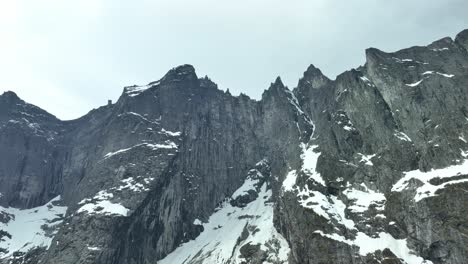 Aerial-looking-up-at-famous-Troll-Wall-in-Norway---Vertical-mountain-wall-famous-for-its-pointy-tops-and-risky-climbing-and-base-jumping-possibilities