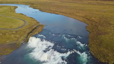 drone view tilting up from faxi waterfall to reveal the icelandic landscape