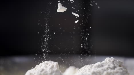 beautiful cinematic and slow motion view of a hand mixing dough and flour in a fancy kitchen, flour falling and flying in the air. particles and specks of flour suspended in the air.