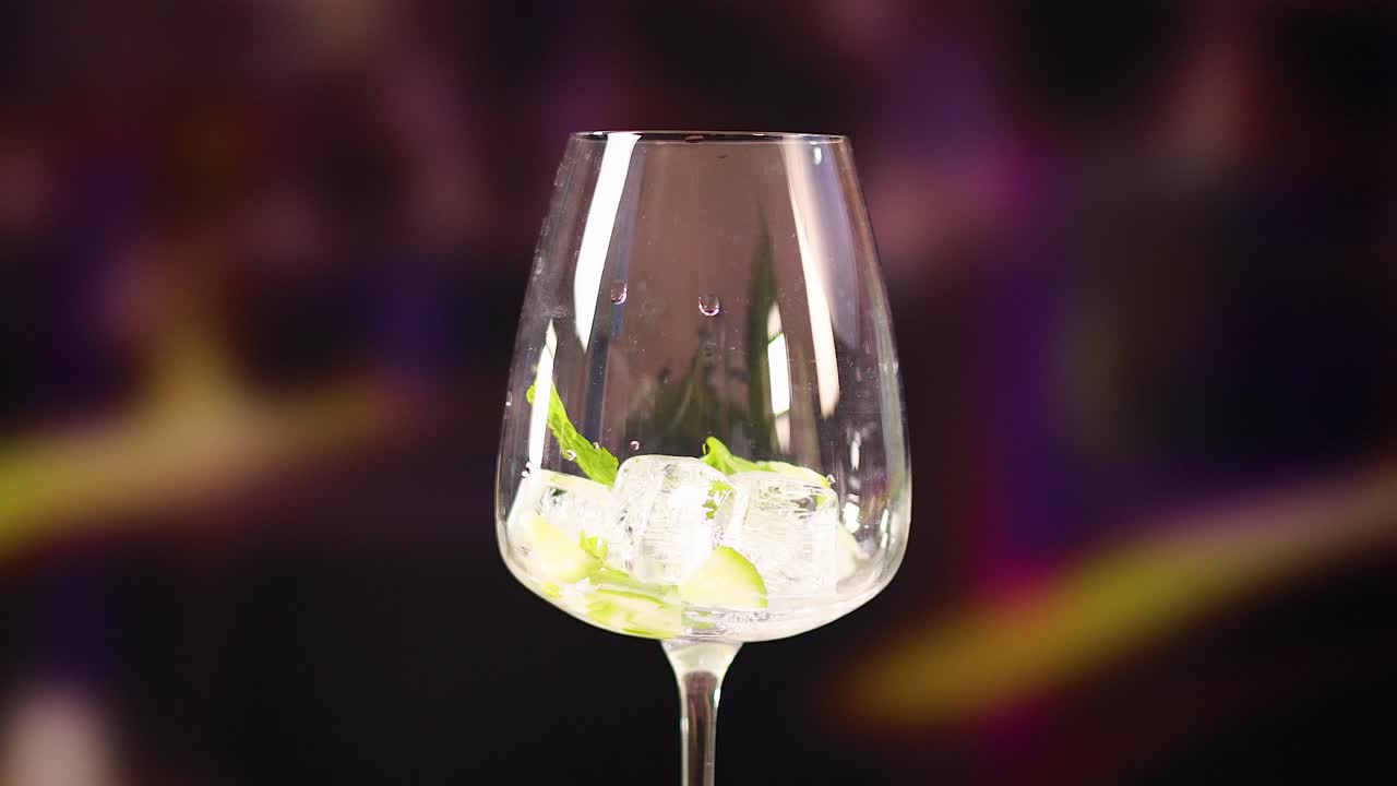 A glass with lime and ice is prepared for a mojito cocktail in a lively, colorful environment