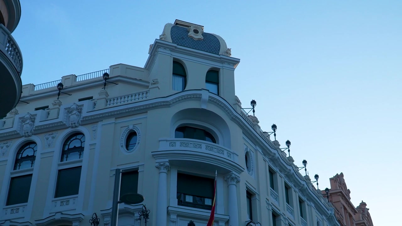 Vista en ángulo bajo de edificios clásicos ornamentados y balcones en el centro de Madrid. Ideal para documentales de viajes, historia europea y contenido sobre estilo de vida urbano.