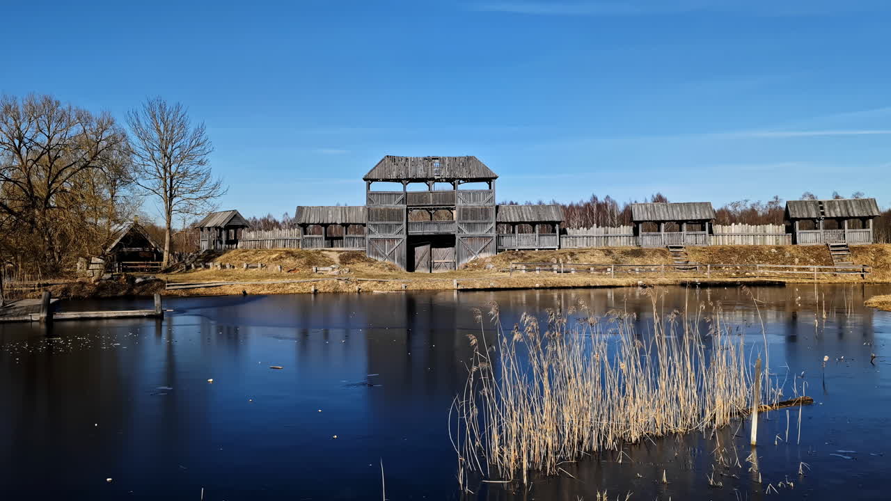 Medieval wooden fortress with moat on a sunny day surrounded by nature