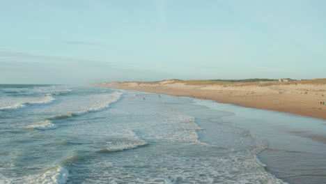 Gente-Disfrutando-Del-Tiempo-En-La-Playa-En-California-En-La-Hermosa-Luz-De-La-Tarde,-Alto-ángulo-Aéreo-Dando-Vueltas-Lentamente