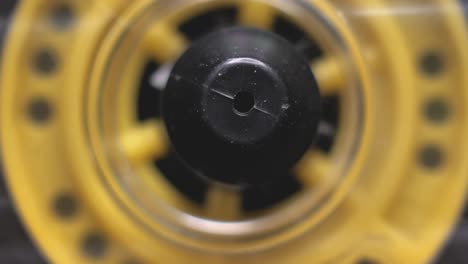 macro yellow transparent audio cassette in the tape recorder. playing and rotating. close up, front view reel.