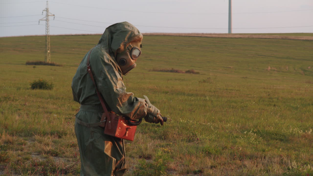 Pessoa usando um traje de proteção e máscara de gás mede e coleta dados na área contaminada