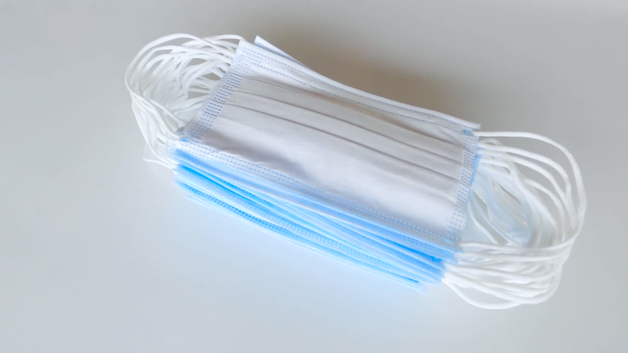 covid-19 검역소에서 일상적인 건강 관리를 위해 흰색 테이블에 의료용 수술용 마스크를 들고 있는 사람