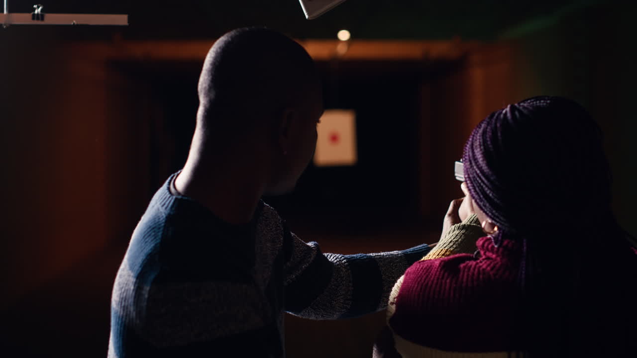 총격장 전문가가 권총을 들고 있는 여성에게 가이드를 제공합니다.