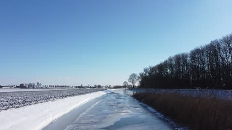 drone flies over a ditch in a dutch winter landscape