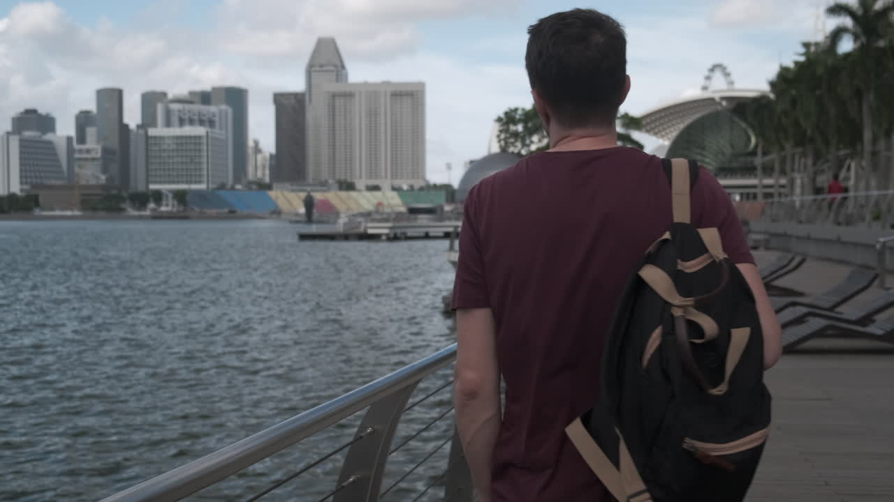 hombre con mochila caminando a lo largo de la marina en singapur