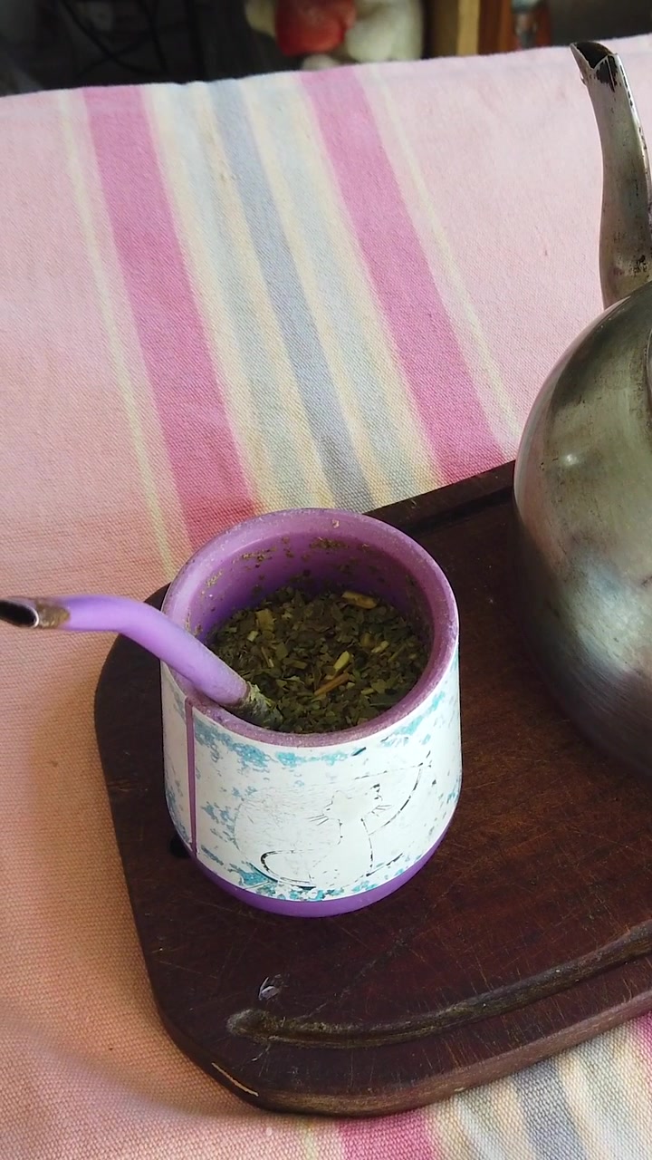Primo piano verticale di una zucca tradizionale per Yerba Mate con bombilla e bollitore su un vassoio di legno.
