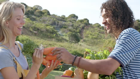 happy diverse couple holding basket of fresh vegetables in garden, slow motion