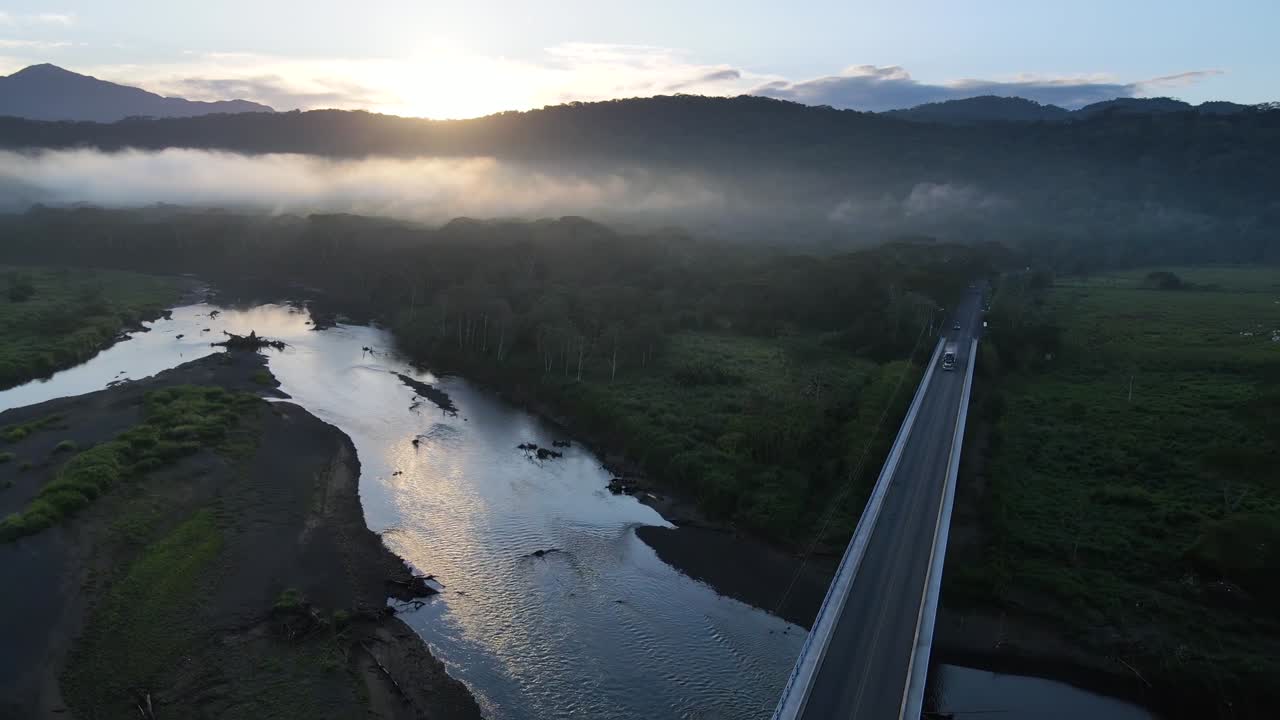 Aerial footage over a bridge early in the morning.