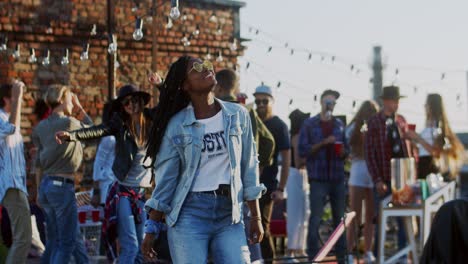 young stylish and pretty girl dancing joyfully and nice in front of the camera at the rooftop party