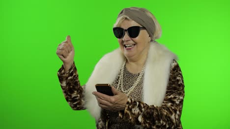 mujer abuela caucásica usando un teléfono inteligente, señalando algo con la mano