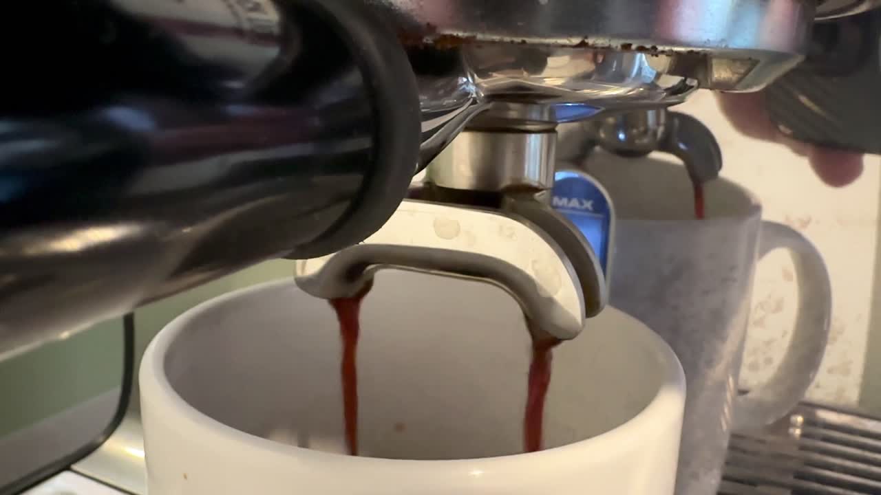 Espresso Coffee machine closeup pouring from spouts brewing in kitchen.