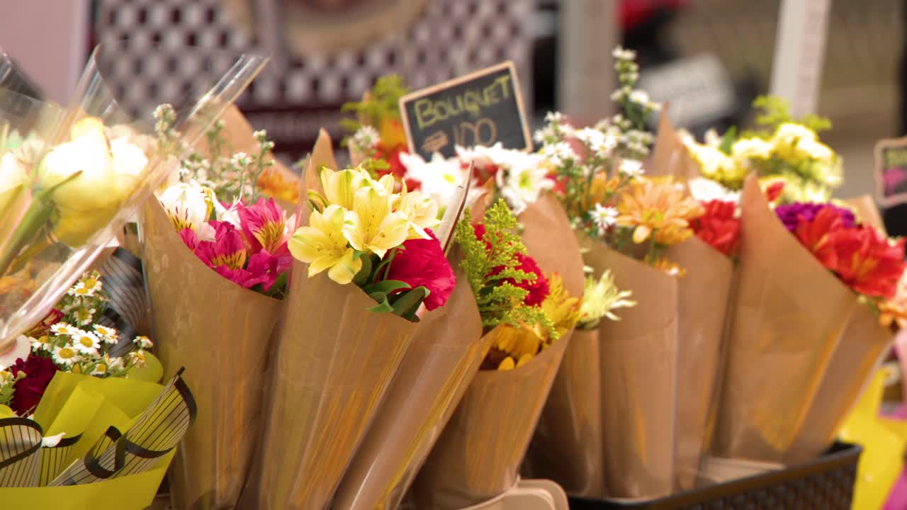 Nærbillede af farverige blomsterarrangementer i brunt papir ved en filippinsk gadebod.