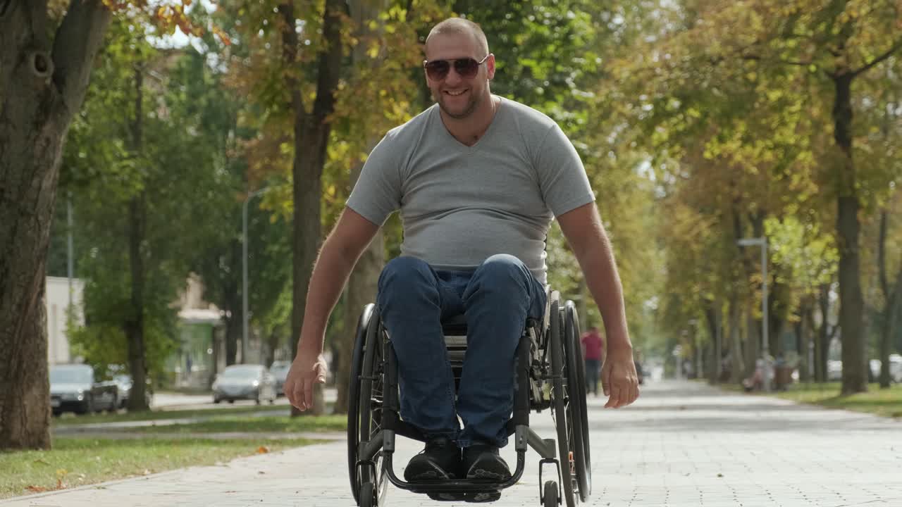 Happy Man with disabilities in wheelchair walk at the park alley