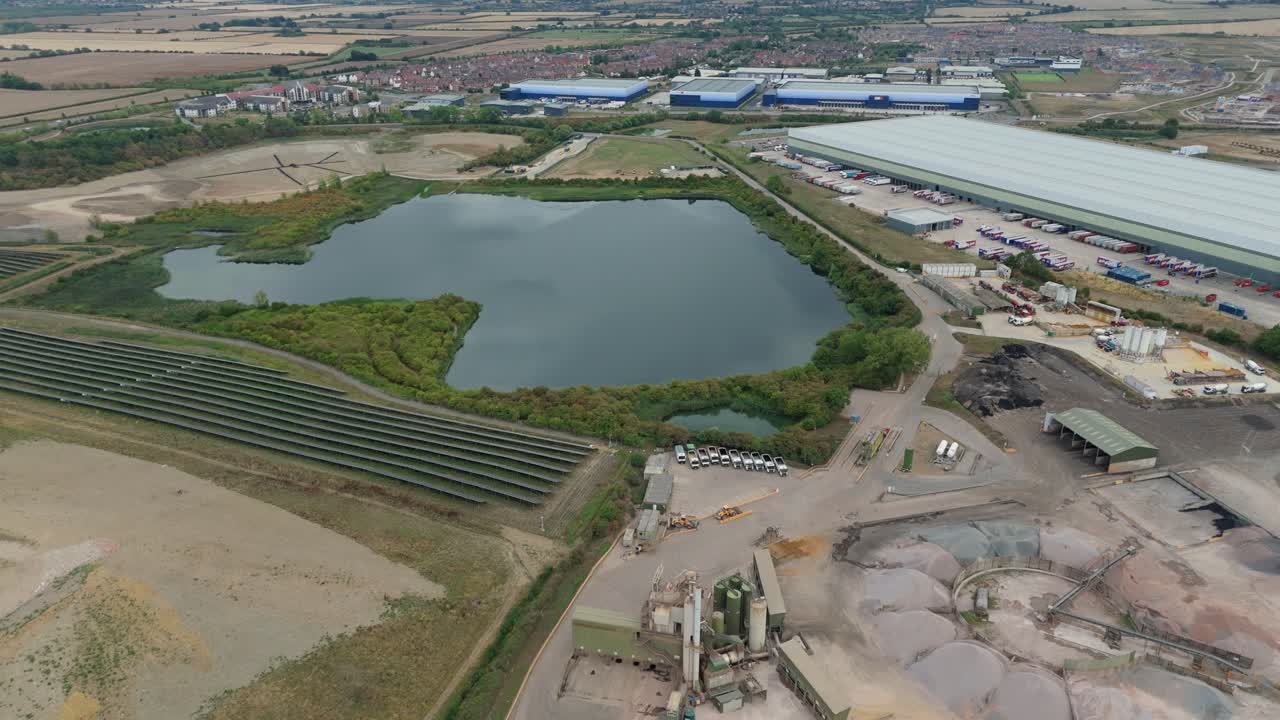 Aerial drone video of Bedfordshire warehouse hub, solar panel rooftops and aggregates site showing industrial production and infrastructure in UK