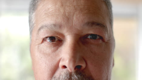 Retrato-De-Cerca-De-Los-Ojos-Abiertos-De-Un-Hombre-Birracial-Mayor-Sonriendo-En-Casa,-Cámara-Lenta