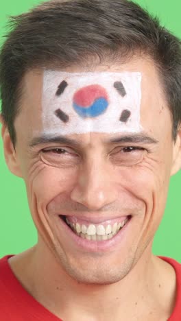 man with a south korean flag painted on the face smiling