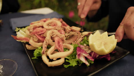 man using fork and knife to eat a mixture of fried fish at the restaurant