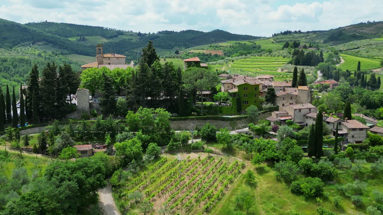 Aerial view of the charming Tuscan village of Montefioralle, perched on a hill. Stone houses, vibrant flowers, and winding streets create a picturesque scene, capturing the essence of rustic beauty