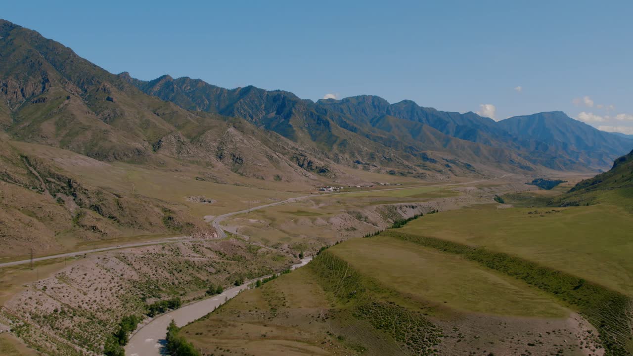Drohnenaufnahme des Zusammenflusses der Flüsse Chuya und Katun in der Altai-Republik, Russland, mit Bergkämmen, sich schlängelndem Flussbett und offenem Steppental.