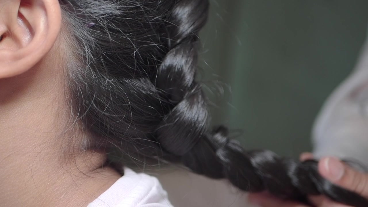 Primo piano di una mano che intreccia lunghi capelli scuri
