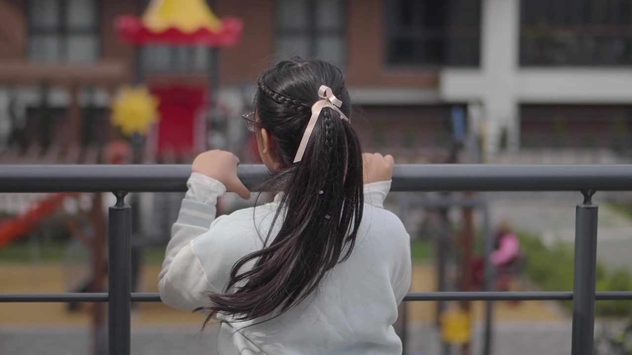 Young Girl with Long Hair Leaning on Railing Outdoors