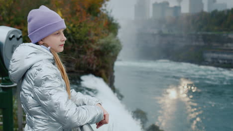 a child admires the spectacular landscape at niagara falls. stands on the american side overlooking the canadian coast