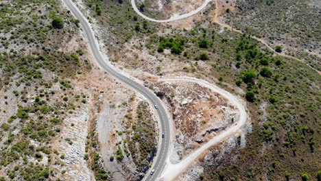 imágenes de aviones no tripulados desde una altura filmando algunos coches a distancia, conduciendo en una carretera en las colinas de españa