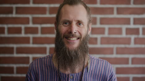 portrait-mature-bearded-hippie-man-smiling-happy-enjoying-relaxed-carefree-lifestyle-eccentric-caucasian-male-wearing-nose-ring-on-brick-wall-background