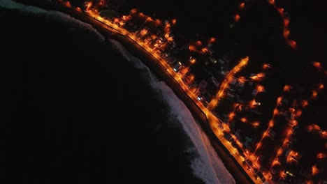 admire the beauty of madeira as the sun sets, with dramatic waves crashing on the coastline and the city lights twinkling along the water's edge, all captured from a breathtaking drone perspective