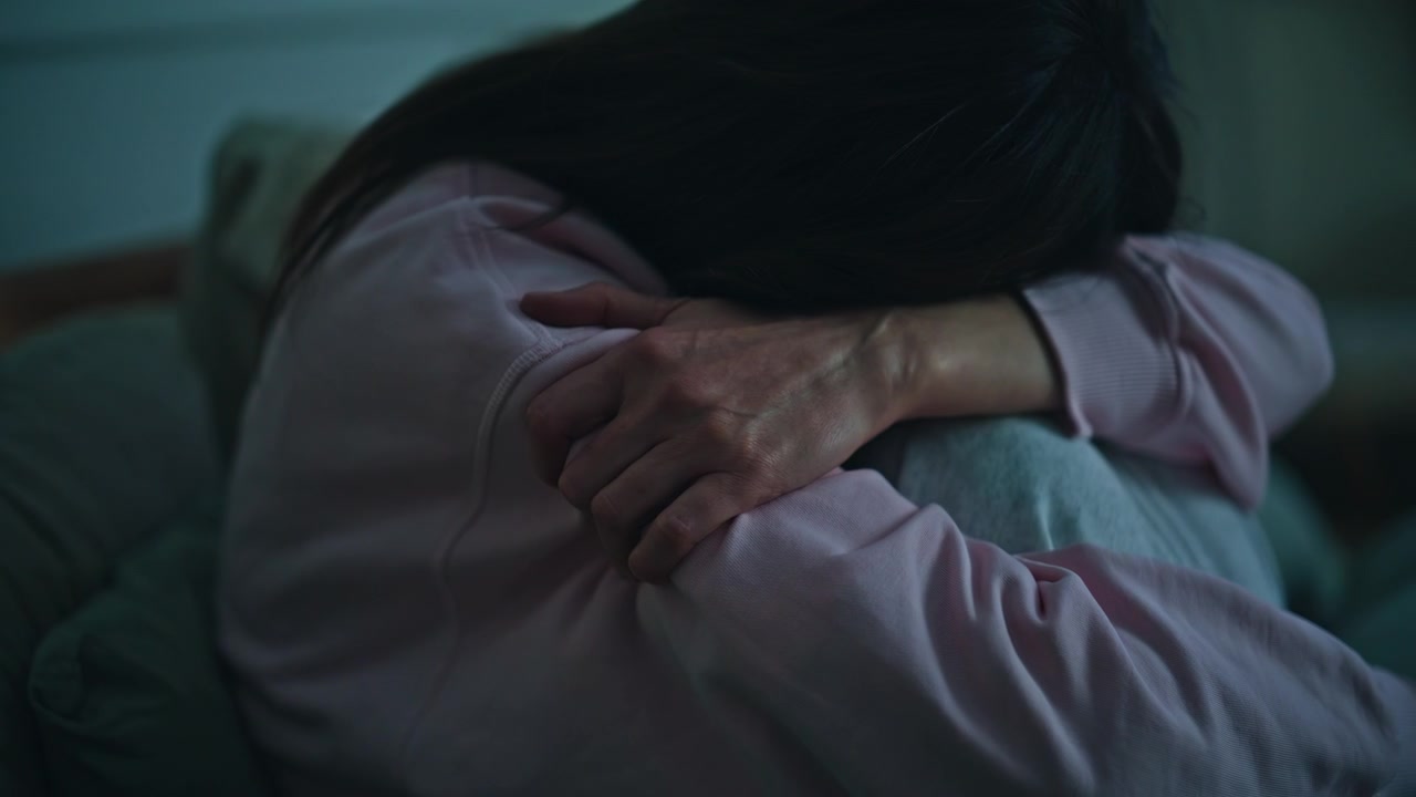 夕方の寝室でうつ病に苦しむ悲しい女性のクローズアップ。孤独なブルネットの女性。