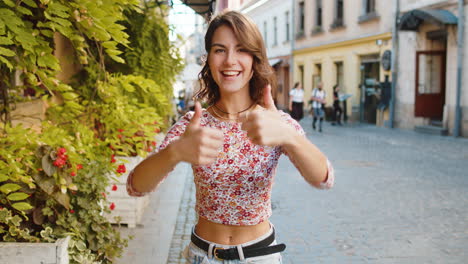 Young-woman-showing-thumbs-up,-like-sign-positive-something-good-positive-feedback-in-city-street