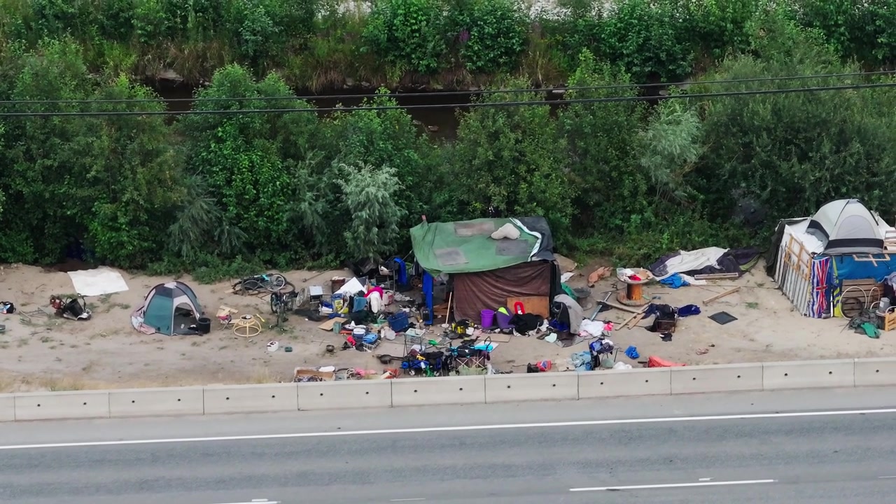 Tende e rifugi per senzatetto accanto a una strada trafficata