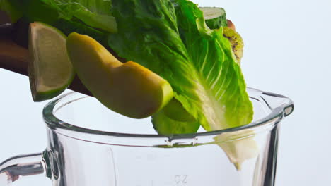 frutas y verduras caen en el cuenco de la licuadora de primer plano. verduras caídas en el aparato de mezcla