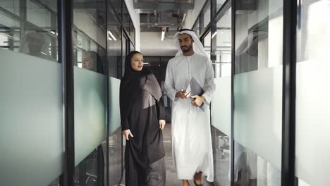handsome man and woman with traditional clothes working in an office of dubai