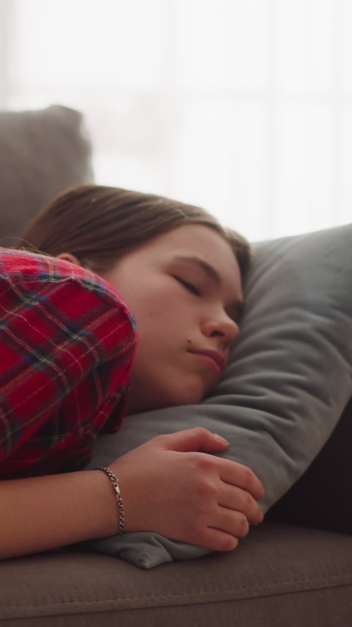 una joven bastante cansada con ropa casual duerme en un cómodo sofá con una almohada suave en casa en close-up en cámara lenta. una mujer tranquila se relaja en un lugar acogedor para descansar