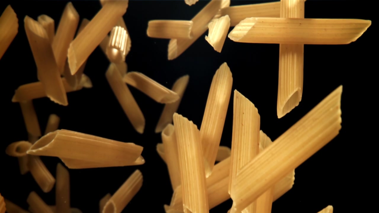 Pasta penne che cade al rallentatore su sfondo nero