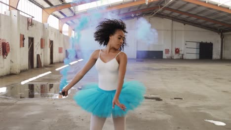 Female-dancer-in-an-empty-warehouse-holding-smoke-grenade