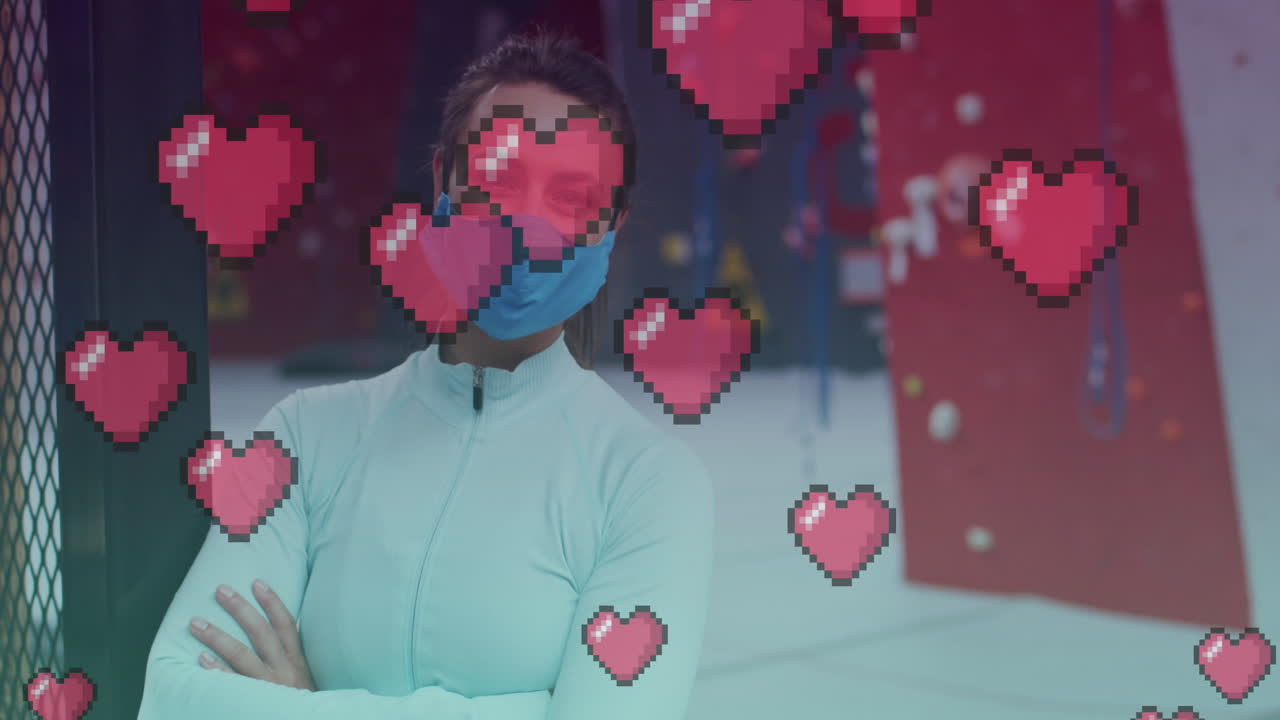 체육관에서 마스크를 착용한 백인 건강한 여성의 초상화에 대해 떠다니는 분홍색 심장 아이콘